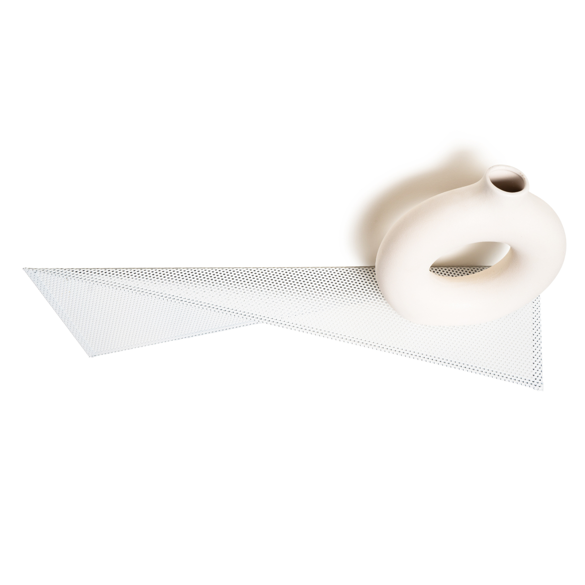 Perforated metal wall shelf with a triangular design, paired with a round white ceramic vase. A functional and stylish addition to any space.